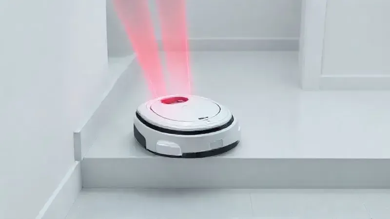 Ilustração de um aspirador robô parando na beirada de um degrau, com feixes de luz vermelha mostrando a tecnologia do sensor anti-quedas em ação.